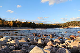 Scenic rocky shoreline with autumn forest and blue sky