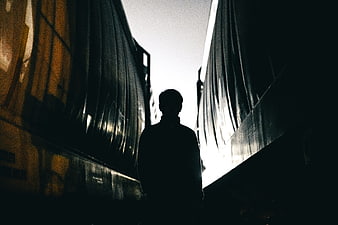 Silhouette of man standing between large trucks