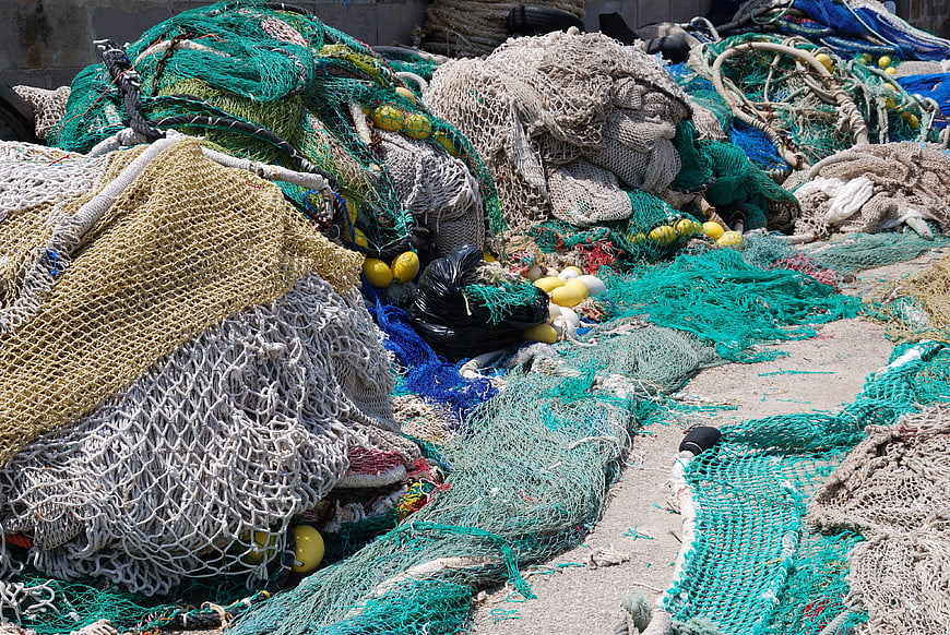Piles of colorful fishing nets and buoys on concrete dock