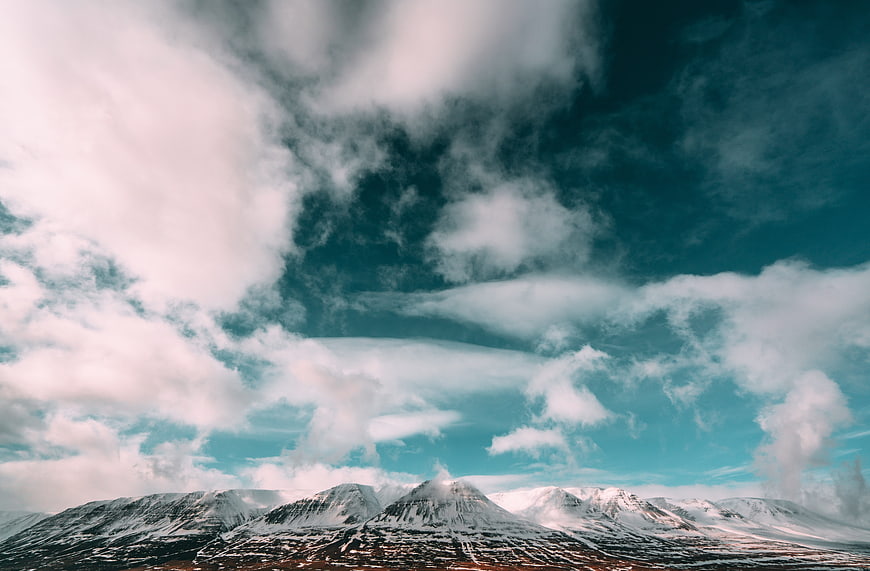 Snow-Capped Alpine Mountains Under Dramatic Teal Sky
