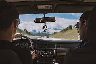 Two men driving vintage car on mountain road trip