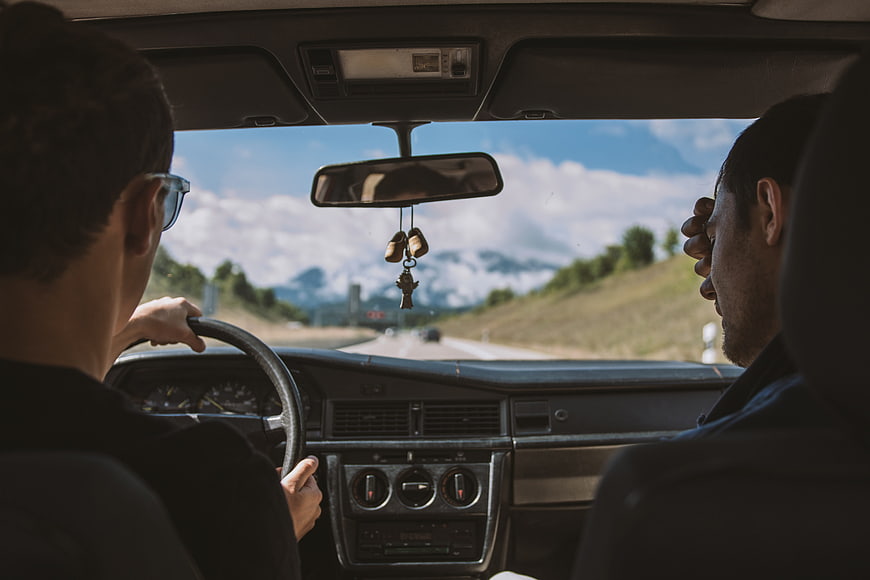 Two men driving vintage car on mountain road trip
