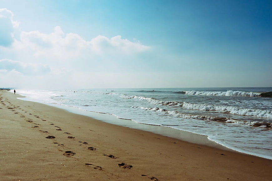 Sandy Beach Shoreline with Footprints and Ocean Waves