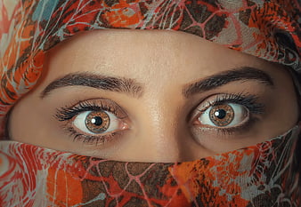 Close-up of woman's eyes wearing patterned orange hijab