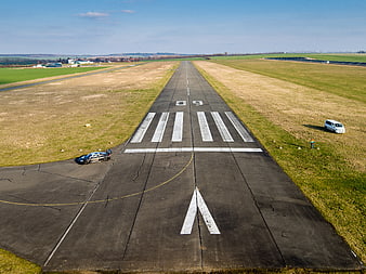 Aerial view of race car on airport runway with grassy fields