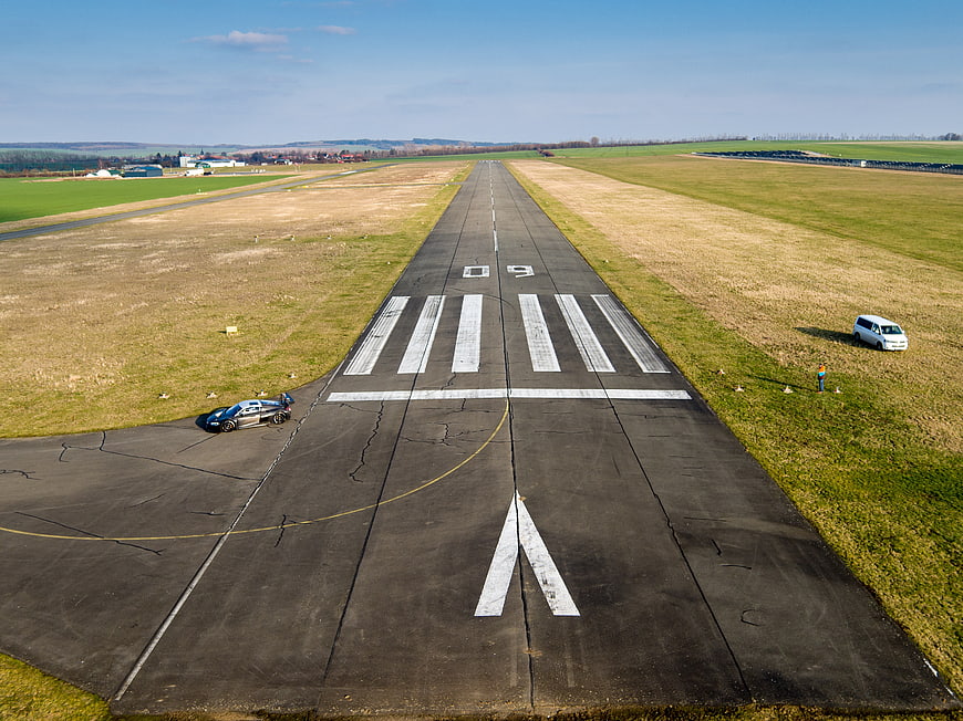 Aerial view of race car on airport runway with grassy fields