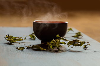 Steaming Cup of Hot Green Tea with Dried Leaves
