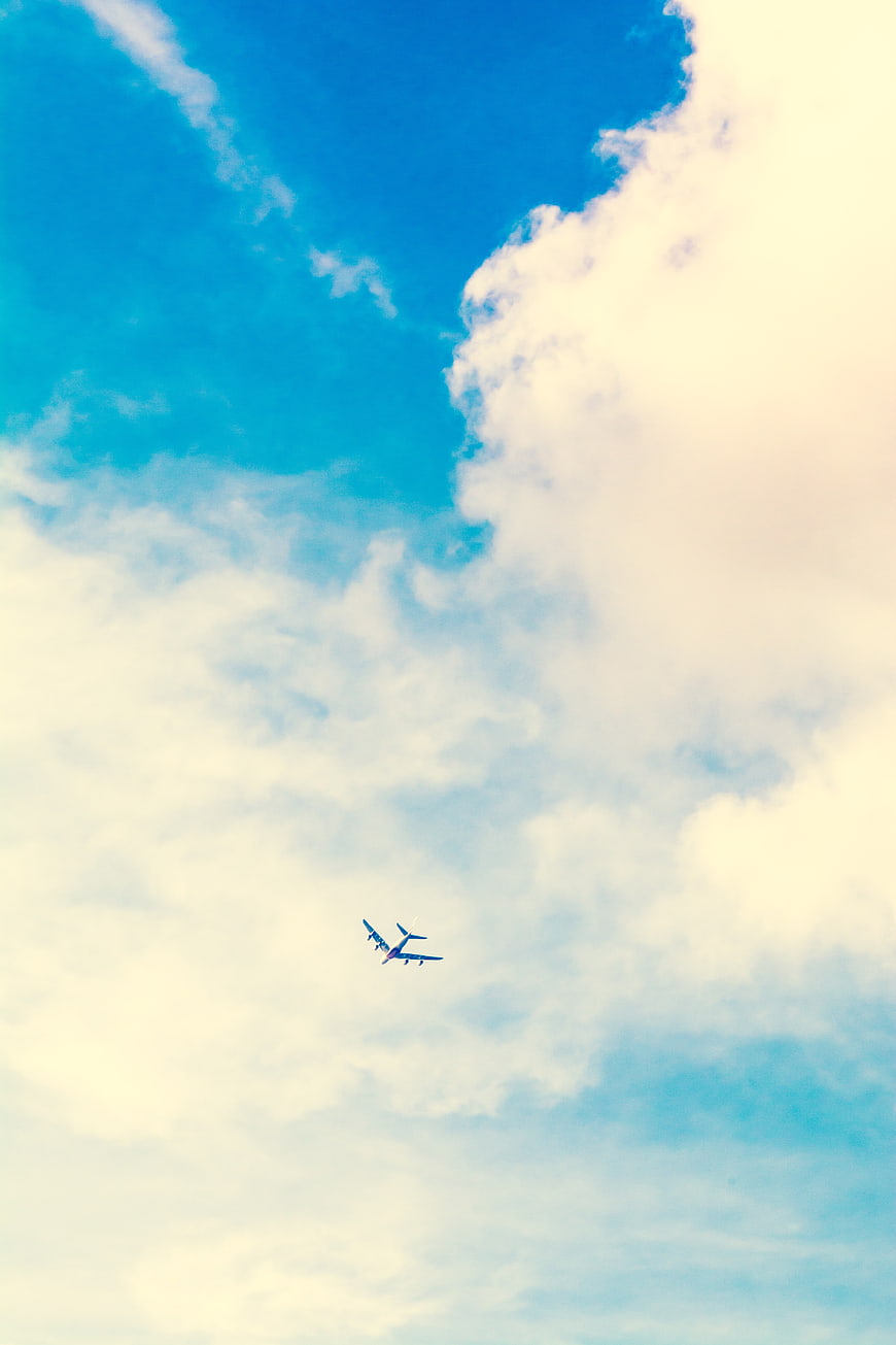Airplane flying high in blue sky with clouds