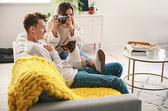 Couple taking photo of dog with vintage camera at home