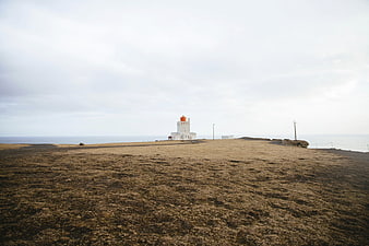 White Lighthouse on Coastal Cliff with Dry Grass