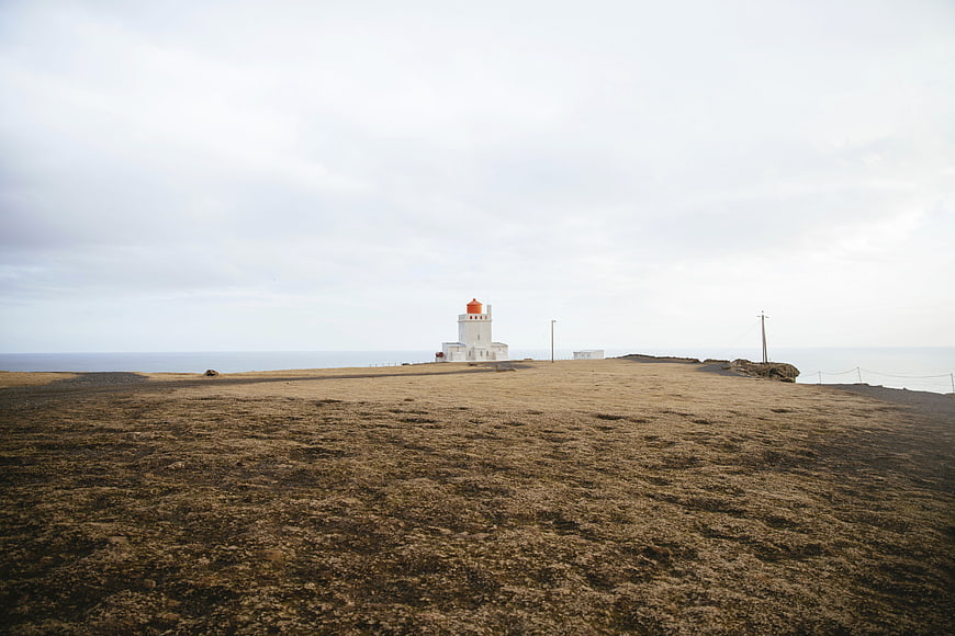 White Lighthouse on Coastal Cliff with Dry Grass