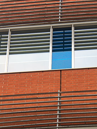 Modern Brick Building Facade with Horizontal Metal Louvers and Blue Window