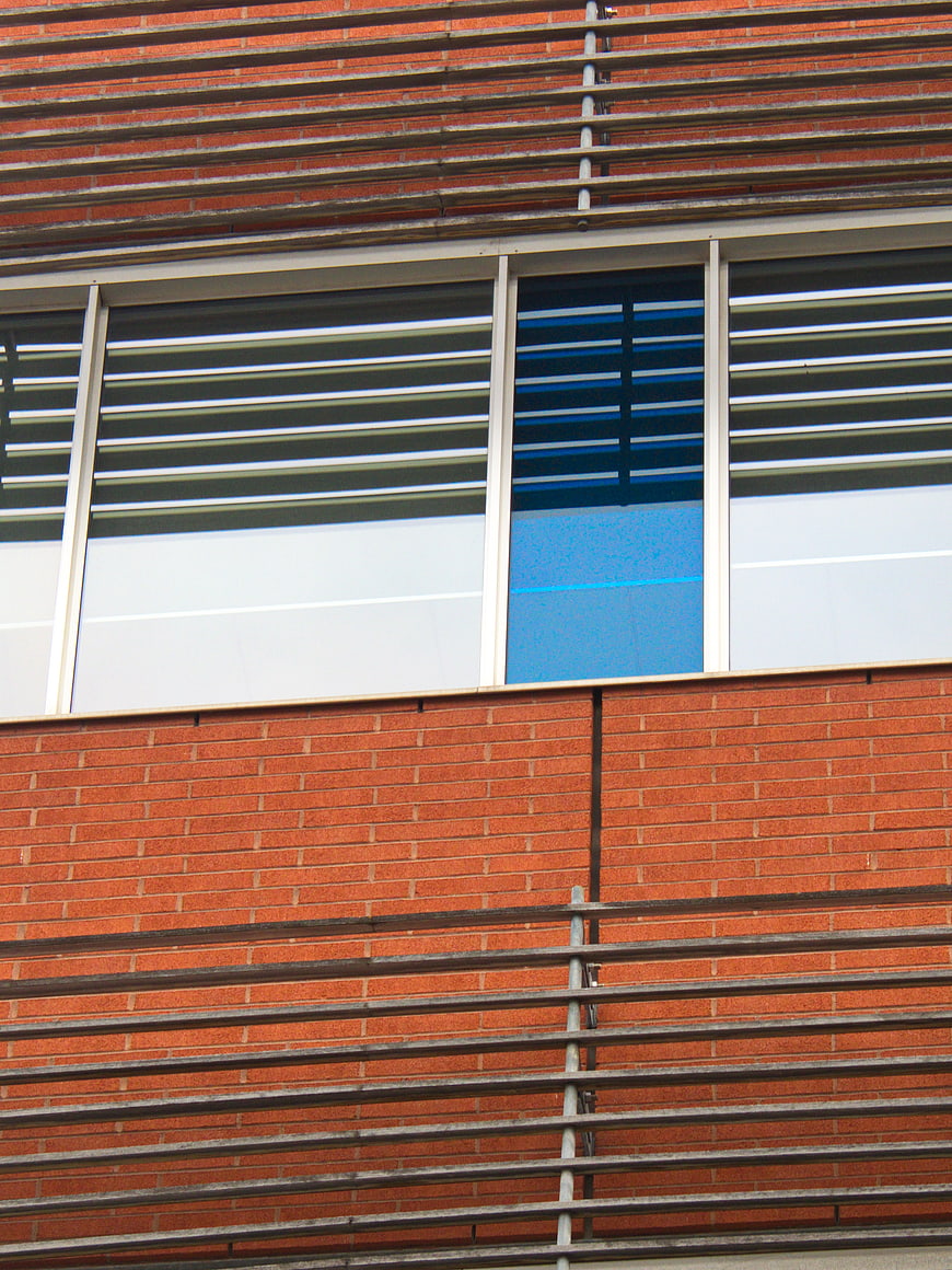 Modern Brick Building Facade with Horizontal Metal Louvers and Blue Window