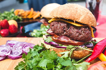 Gourmet burger with bacon, cheddar, and guacamole on wooden board
