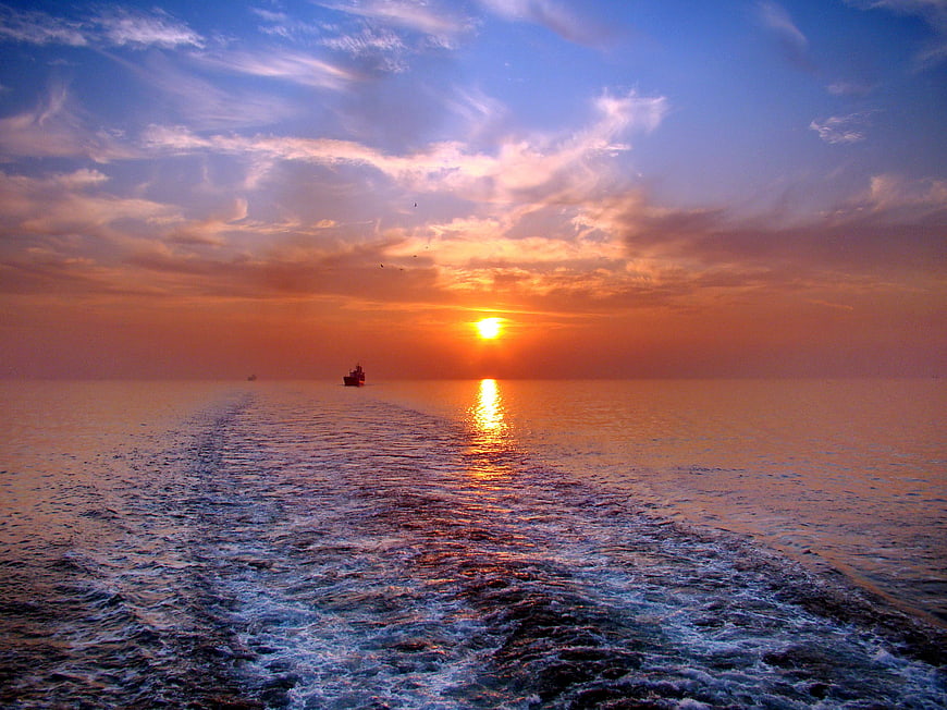 Ocean Sunset With Ship Wake And Sun Reflection On Water