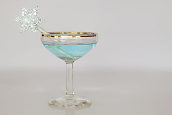 Blue Holiday Cocktail with Snowflake Garnish in Gold-Rimmed Glass
