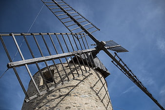 Low angle view of old stone windmill against blue sky