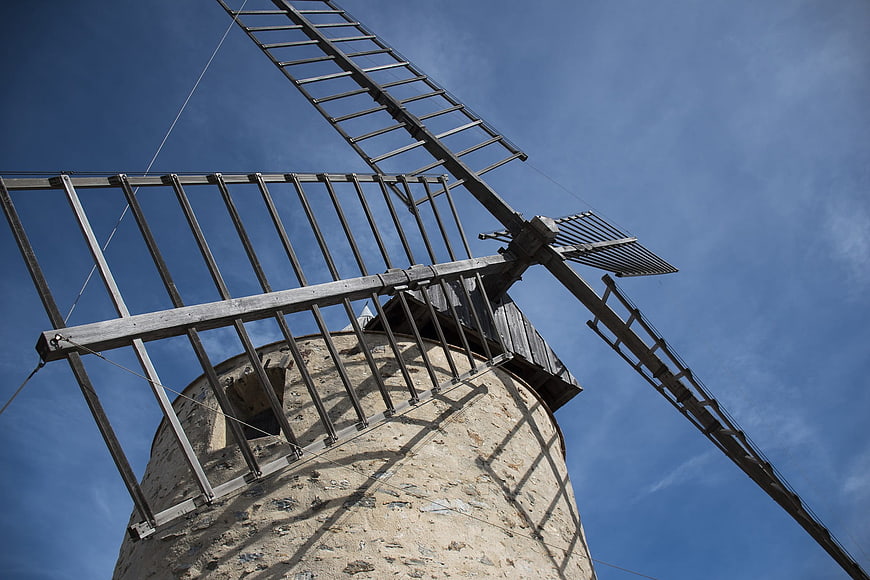 Low angle view of old stone windmill against blue sky