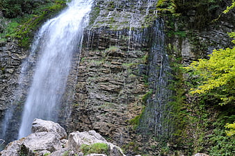 Majestic waterfall cascading down rocky cliff in lush forest