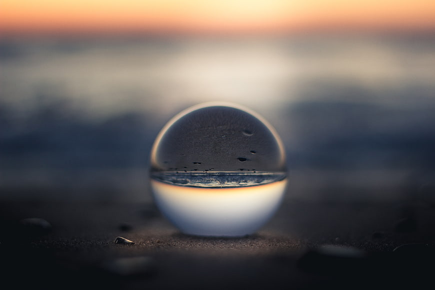 Crystal clear glass sphere on a beach at sunset