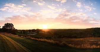Golden Sunrise Over Rolling Green Hills and Pastoral Landscape