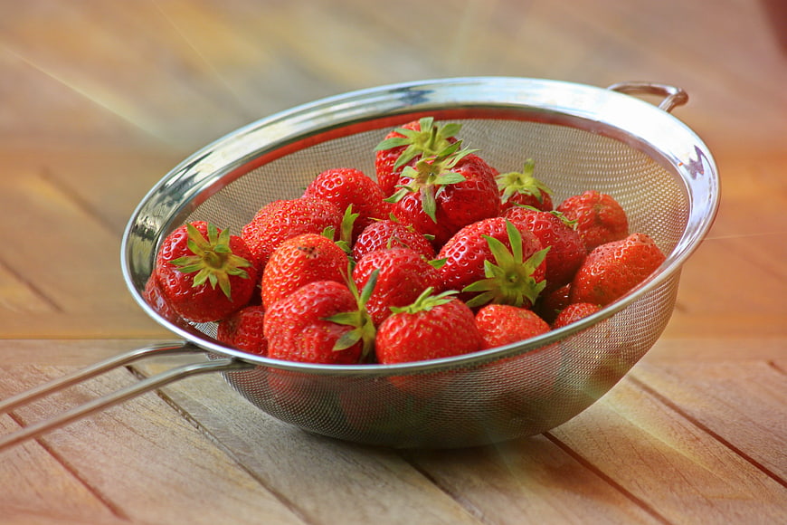 Fresh Ripe Strawberries In Metal Strainer On Wooden Table