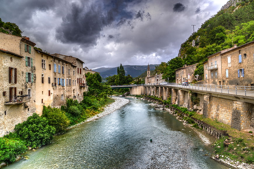 Scenic River in Old French Town with Stone Buildings and Bridge