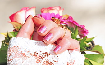 Close-up of pink glitter manicure with wedding bouquet
