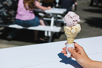Hand holding two scoops of ice cream cone outdoors