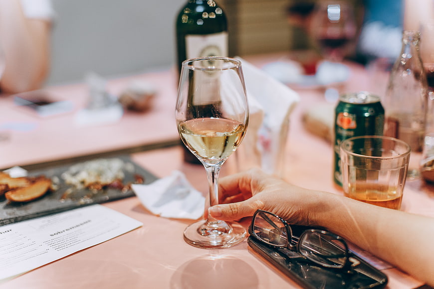 Hand holding white wine glass at restaurant table