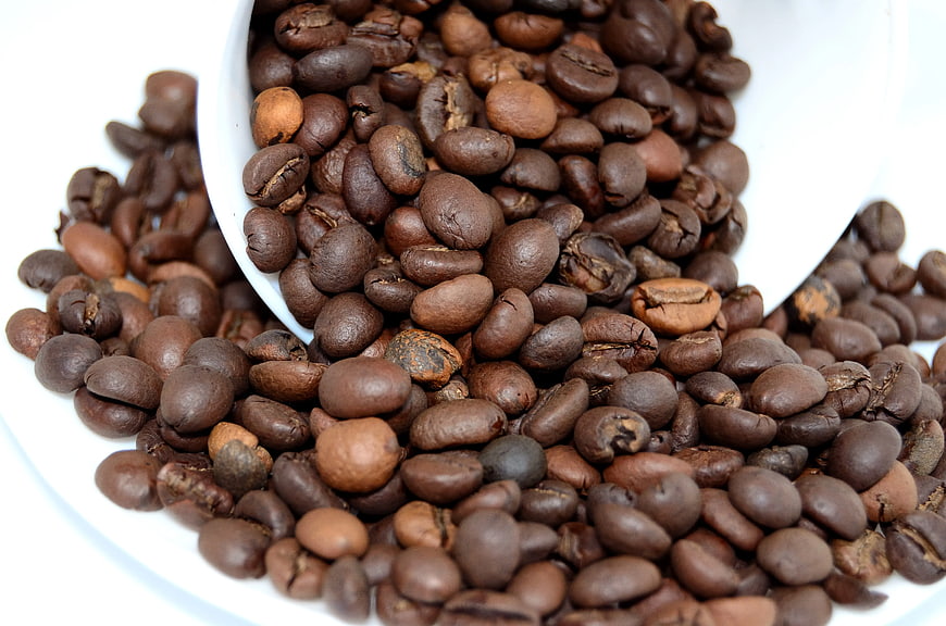 Roasted Coffee Beans Spilling from White Cup