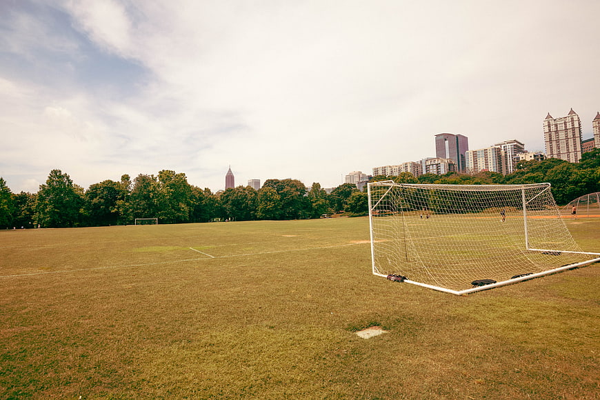 Empty Soccer Field with Goal Net and City Skyline Background