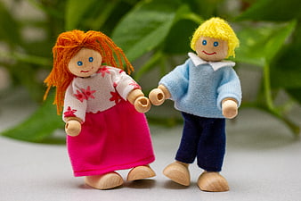 Wooden dolls holding hands with green plant background