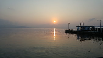 Serene Sunset Over Calm Sea With Silhouetted Pier