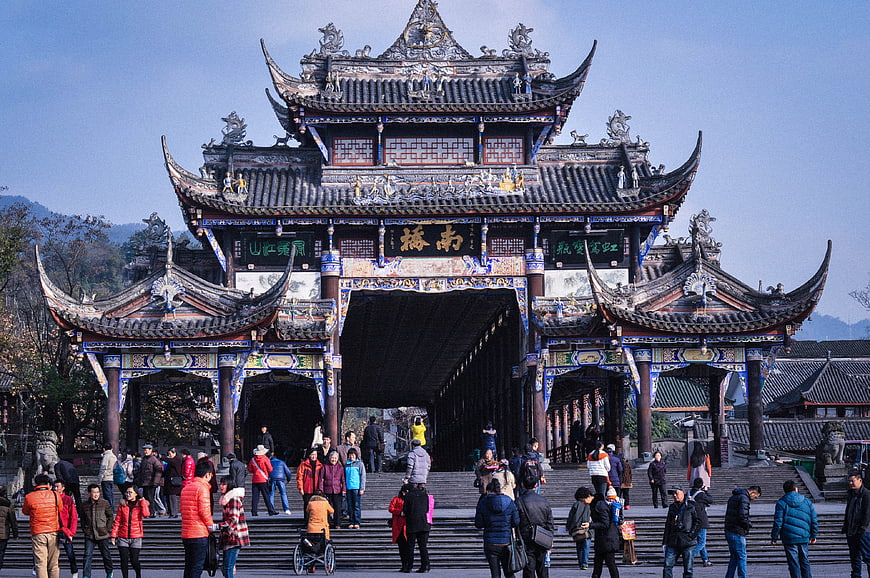 Tourists at ornate traditional Chinese gate in Dujiangyan, Sichuan