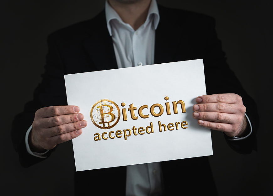 Businessman holding white sign with gold Bitcoin accepted here text