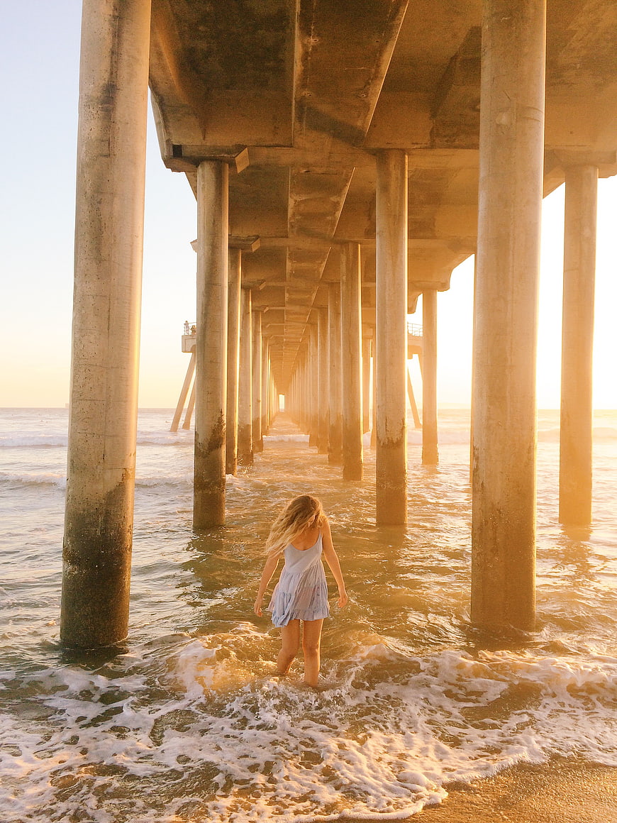 Woman Walking Under Pier at Sunset Beach