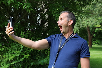 Man taking a selfie with an exaggerated open-mouthed expression outdoors