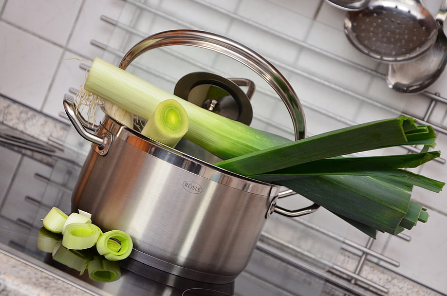 Fresh leeks in stainless steel cooking pot on kitchen counter
