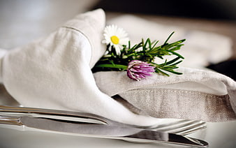 Elegant Table Setting With White Napkin, Cutlery, And Fresh Floral Garnish