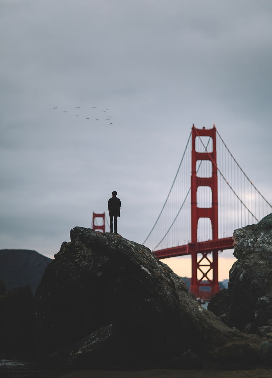 Silhouette of Man Standing on Rock with Golden Gate Bridge