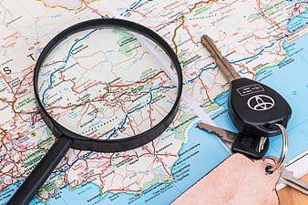 Car keys and magnifying glass on a road map