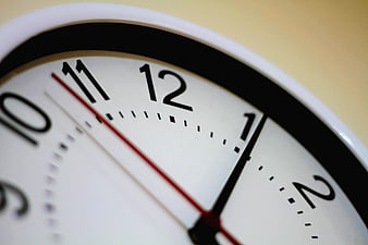 Close-up of analog clock face showing 12:05 with red second hand