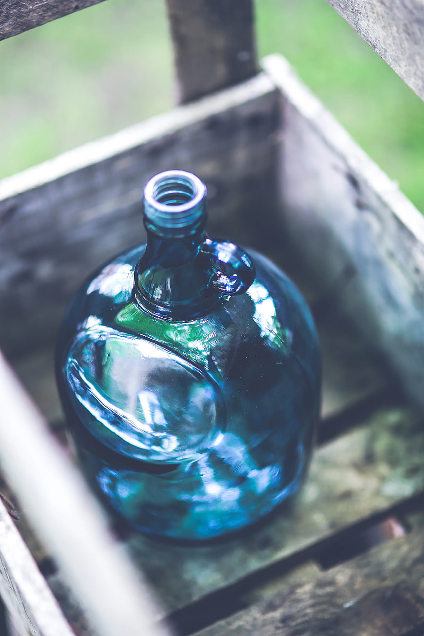 Vintage blue glass demijohn in rustic wooden crate