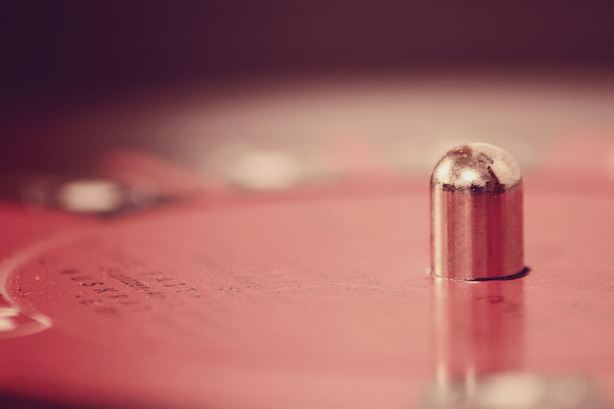 Close-up of a silver rivet on a red vinyl record surface