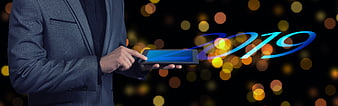 Businessman in suit using tablet with 2019 graphic and bokeh lights