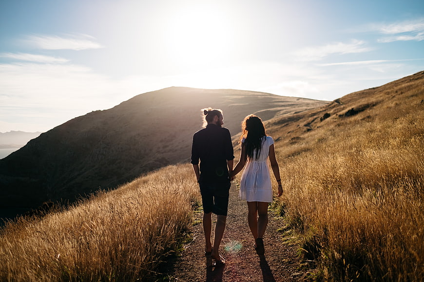 Couple Walking Hand in Hand on Mountain Trail at Sunset