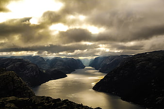Dramatic Fjord Landscape with Golden Sunlight Breaking Through Clouds