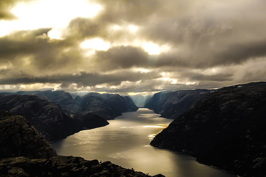 Dramatic Fjord Landscape with Golden Sunlight Breaking Through Clouds