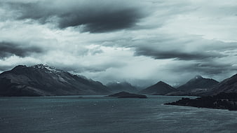 Dramatic moody landscape of mountains and lake under stormy clouds